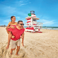 Playing in the sand near colorful lifeguard stands in Miami Beach, Florida